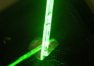 Mirror on speaker with reflected green laser light